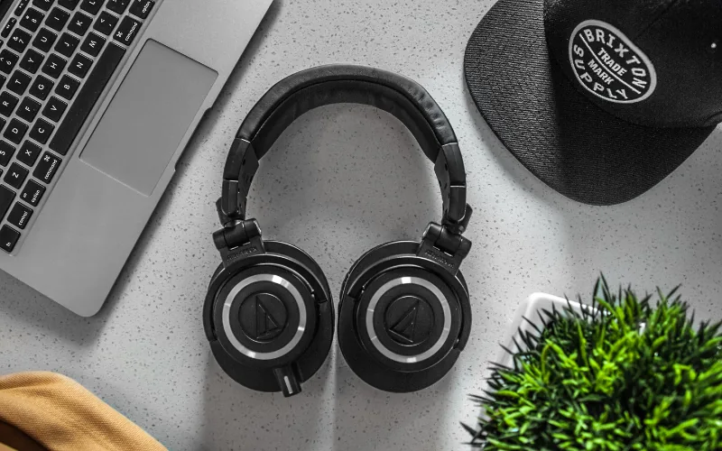 Black headphones on a desk beside a laptop