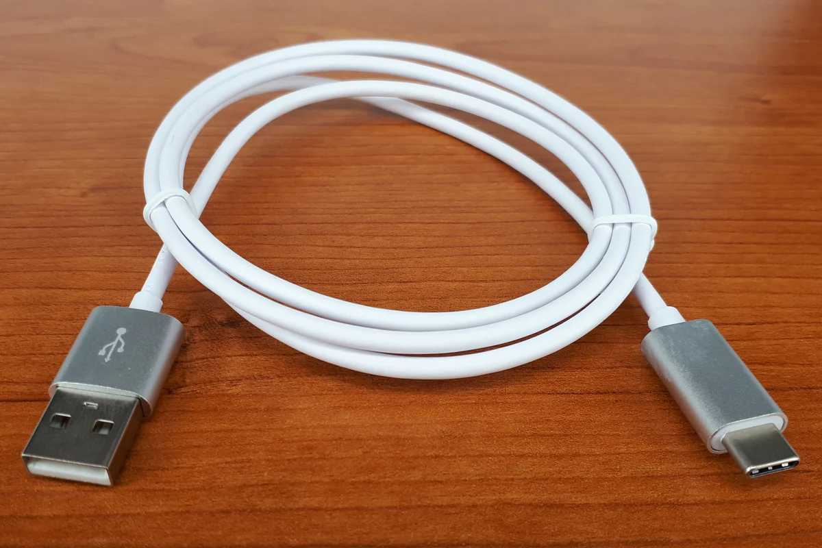 Coiled white USB-A to USB-C cable on a wooden surface.